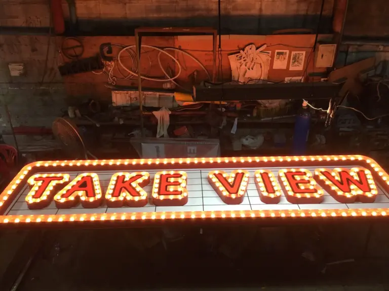 ป้ายตัวอักษร TAKE VIEW มีไฟปิงปองเรียงรอบขอบป้าย