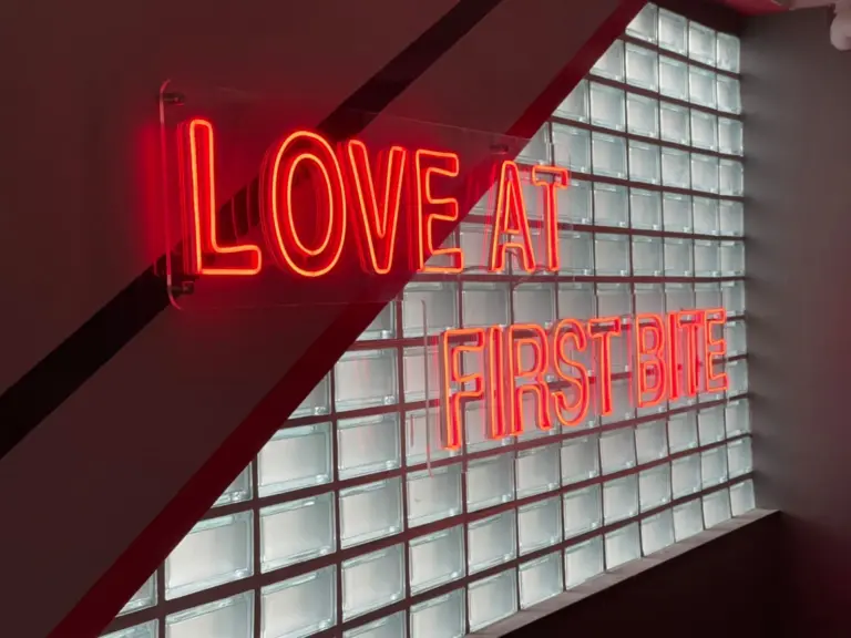 ไฟนีออนเฟล็กซ์ข้อความ LOVE AT FIRST BITE บนผนังบล็อกแก้ว